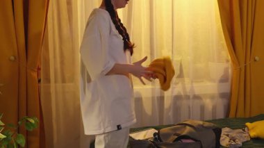 Çekici Kafkasyalı kadın, seyahat için gerekli olan giysileri hazırlıyor eşyaları düşürüyor ve seyahat hazırlıklarını düzenliyor. Yan görünüm, kapat.