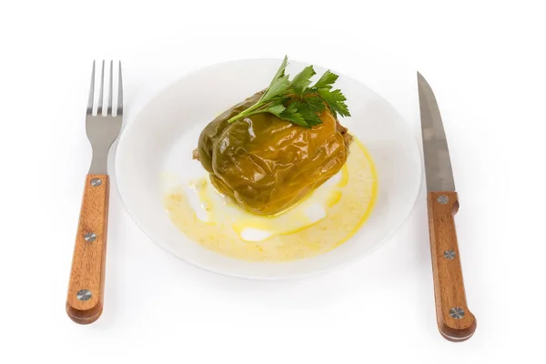 白皿の上に米と刻んだ肉を詰め黄色の鐘唐辛子と緑の部分 白の背景にフォークとナイフ — ストック写真