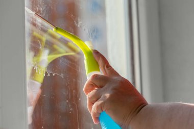 Pencere temizliği sırasında düz cam yüzeyler için sprey şişesi olan yerli plastik kazıyıcı, seçici odak