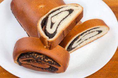 Haşhaş tohumu rulosunun diğer kısımlarında ahşap masadaki beyaz tabakta, yakın plan.