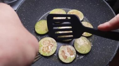 Kızartma tavasında yuvarlak patlıcan dilimleri ters döner.