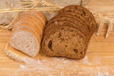 Çavdar ekmeği, buğday unu ve ekmeği dilimlenmiş iki somun koyu kahverengi ekmek farklı kulaklar arasında kepek ve un ile saçılmış buğday taneleri.