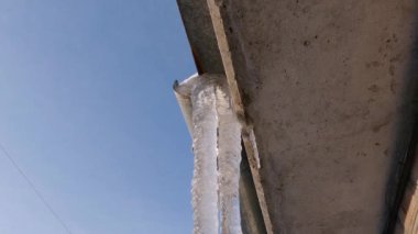Endüstriyel binanın çatısındaki buz saçakları gökyüzüne karşı