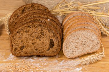 Çavdar ekmeği, buğday unu ve ekmeği dilimlenmiş iki somun koyu kahverengi ekmek farklı kulaklar arasında kepek ve un ile saçılmış buğday taneleri.