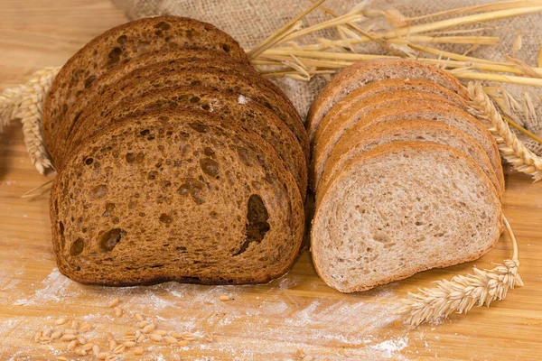 Çavdar ekmeği, buğday unu ve ekmeği dilimlenmiş iki somun koyu kahverengi ekmek farklı kulaklar arasında kepek ve un ile saçılmış buğday taneleri.