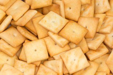 Heap of the small salty crackers of square shape, top view of fragment close-up