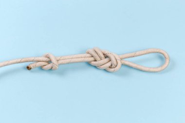 Rope knot as igure-eight loop, also known as Flemish loop with overhand stopper knot on a blue background