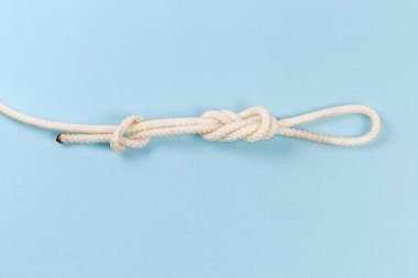 Rope knot as igure-eight loop, also known as Flemish loop with overhand stopper knot on a blue background
