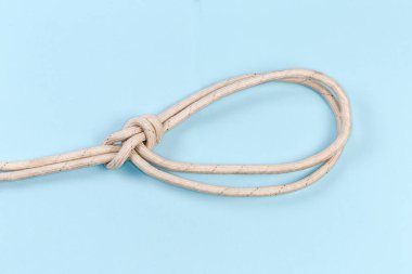 Rope knot bowline on a bight intended to make pair of fixed-size loops in the middle of a rope, view on a blue background