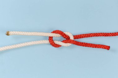 Rope grief knot, similar to reef knot, but impractical and used as device for trick, view on a blue background