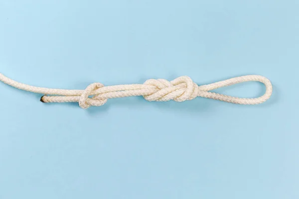 Rope knot as igure-eight loop, also known as Flemish loop with overhand stopper knot on a blue background