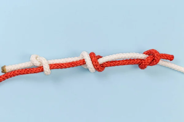 Tightened rope fisherman knot, also known as English or weaving knot in climbing, used for connecting of two ropes of the same diameter with stopper knots, view on a blue background