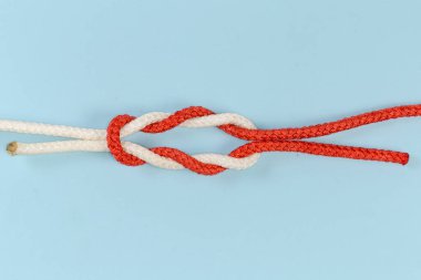 Not tightened rope double reef knot, modification of the surgeon's knot containing two each double overhand knots in the bottom and on the top on a blue background