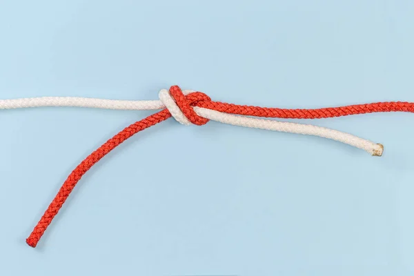 Rope water knot, also known as tape knot or ring bend on a blue background