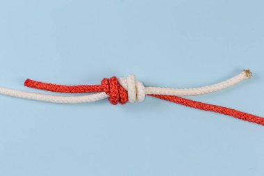 Tightened rope Grapevine knot, also known as double fisherman's knot on a blue background