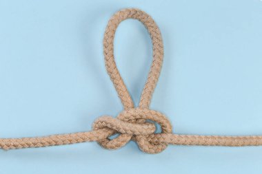 Rope knot Butterfly loop, also known as Swiss loop tied with a climbing rope on a blue background