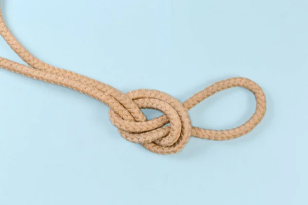 Rope knot Overhand loop, also known as loop knot tied with a climbing rope, close-up on a blue background