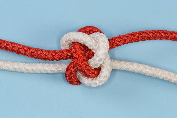 Tightened decorative rope Diamond knot, also known as Knife lanyard knot, view close-up on a blue background