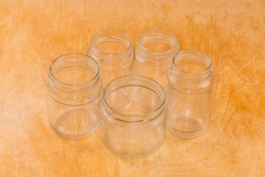 Empty small glass jars different sizes with screw thread on mouth for lids on a wooden surface