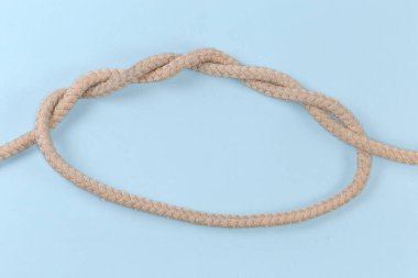 Not tightened rope Threefold overhand knot, as version of multiple overhand knot tied with a thick rope, view on a blue background