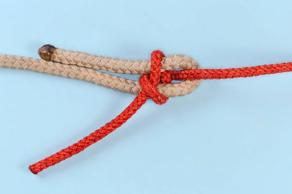 Tightened rope knot Heaving line bend, or messenger-line bend intended to joining two ropes of different diameter or rigidity, view on a blue background