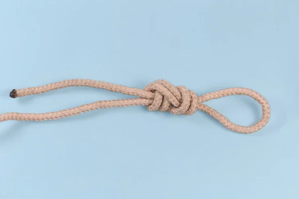 Rope knot Figure-nine loop, also known as Intermediate knot tied with climbing rope, view on a blue background