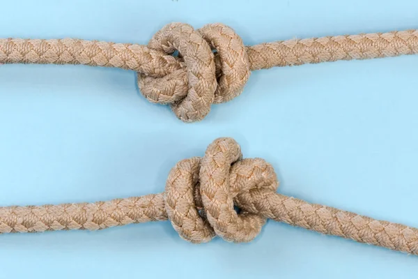 Tightened rope Stevedore knot tied with a climbing rope, view from two sides close-up on a blue background