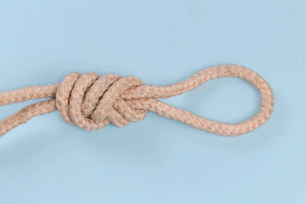 Rope knot Figure-nine loop, also known as Intermediate knot tied with climbing rope, view close-up on a blue background