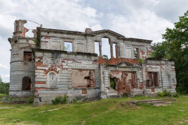 Scenic ruins of the main facade of the old palace in the style of the Italian Renaissance against the forest and cloudy sky