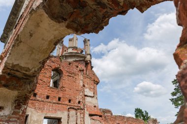 Scenic ruins of the part of the old palace in the style of the Italian Renaissance with tower, view  through an arch in the wall against the cloudy sky