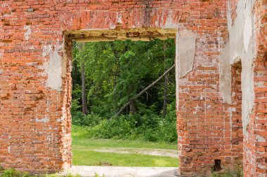 Scenic ruins of the old palace, view of forest through a doorway in the wall of red brick