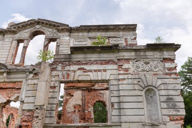 Scenic ruins of the part of main facade of the old palace in the style of the Italian Renaissance against the forest and cloudy sky