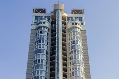 Fragment of top of the facade of the modern multistory building on a background of a clear sky