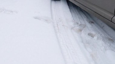 Part of car wheel and tire tracks on a snow