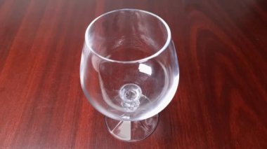 Pouring brandy from bottle to cognac glass on wooden table