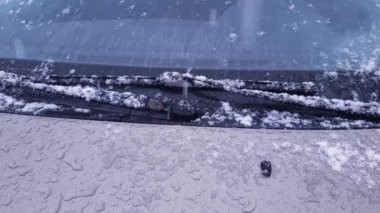 Part of hood and windshield of car during strong snowfall