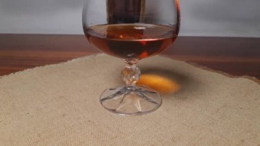 Brandy in cognac glass on textile napkin on wooden table