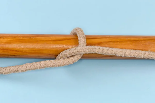绳子结一根绳子绑在一根木杆上 在蓝色的背景上近距离观看 — 图库照片