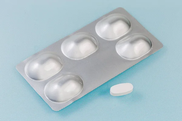 薬の丸薬と青の表面に別々に1本の錠剤で箔ブリスターパック 選択的な焦点 — ストック写真