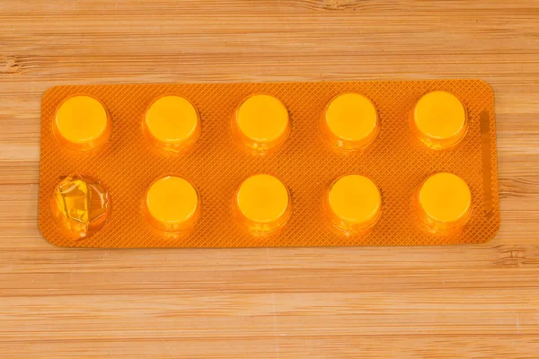 Pacote Blister Amarelo Iniciado Com Pílulas Redondas Medicação Superfície Madeira — Fotografia de Stock