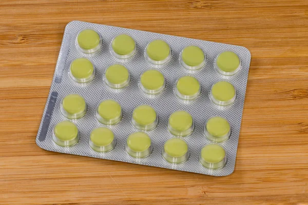 Pílulas Redondas Verdes Blister Uma Superfície Madeira — Fotografia de Stock