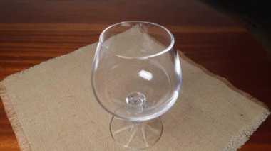 Pouring brandy from bottle to cognac glass on wooden table