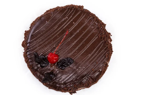 整个圆圆的蛋糕 顶部覆盖着巧克力釉面 上面装饰着深色巧克力片的叶子和樱桃 顶部是白色的背景 — 图库照片