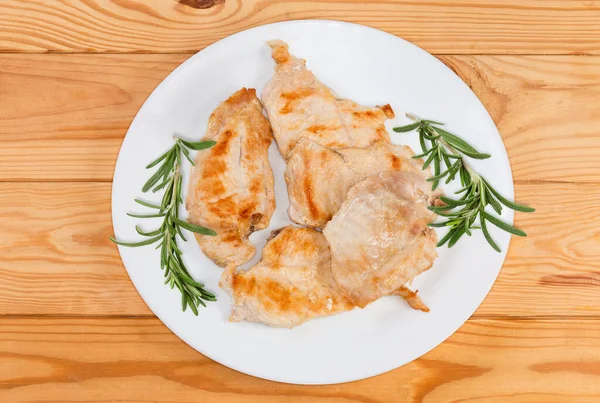 平らなスライスにカット素朴なテーブルの上に皿の上に新鮮なローズマリー小枝で飾られた鶏の胸肉を焼き トップビュー — ストック写真