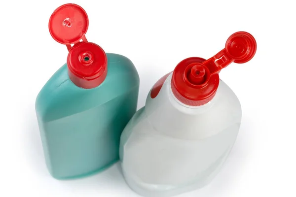 白い背景にオープンレッドの蓋を持つ様々な家庭用洗浄剤の異なる形状と色の2つのプラスチックボトル 選択的な焦点でトップビューのクローズアップ — ストック写真