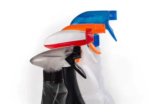 白を背景に様々な家庭用洗浄剤のプラスチックボトルの上に手作業で着色された噴霧器 — ストック写真
