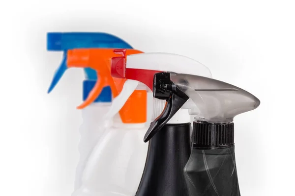 白を背景に同様の色の噴霧器に対する家庭用洗浄剤のプラスチックボトルにグレーの手でポンプ噴霧器 選択的な焦点でクローズアップ — ストック写真
