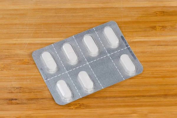 Weiße Pillen Der Gesamten Blisterverpackung Auf Einer Holzoberfläche — Stockfoto