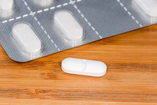 Weiße Längliche Pille Auf Verschwommenem Hintergrund Der Blisterverpackung Derselben Pillen — Stockfoto