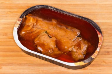 Teneke kutuda Unagi soslu konserve balık, ahşap bir yüzey üzerindeki kapağı çıkarılmış.